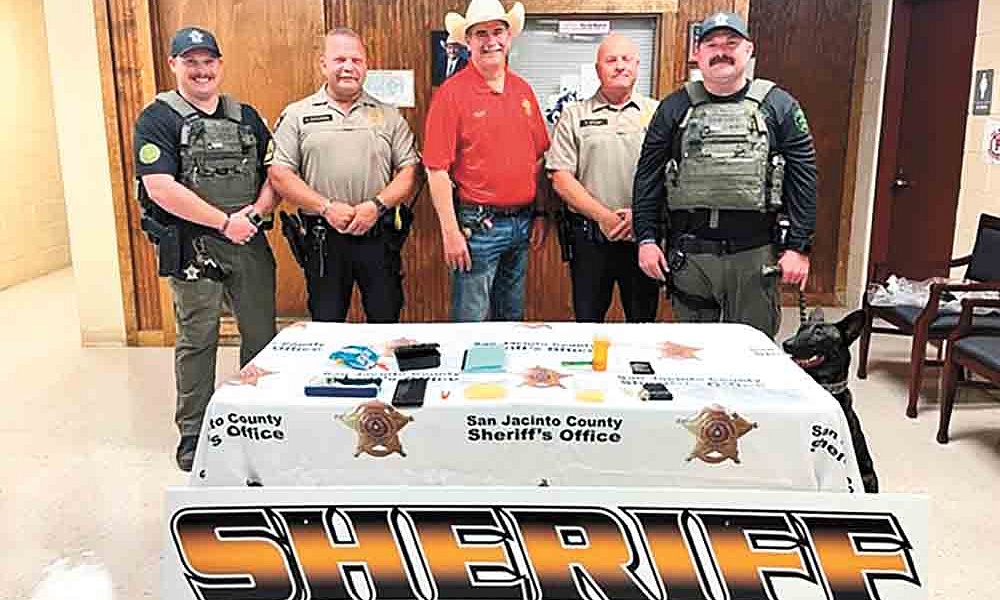San Jacinto County Deputy Jared Oliver, Sgt. Mark Gustafson, Sheriff Greg Capers, Patrol Division Lt. Ray Bowen, K9 Handler Deputy Dustin Oliphant with K9 Lady Duna display a small sampling of the seized drugs and paraphernalia from a recent drug arrest in Cleveland. Courtesy photo
