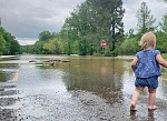 A child walks near a flooded Wolf Creek, along FM 92, on Wednesday. Photo by Stormy Hoyt